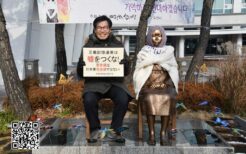烏山市役所（京畿道）の慰安婦像と日本語のプラカードを手にする金柄憲氏